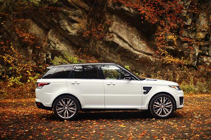 Range Rover Sport in front of a rock wall surrounded by fall foliage side view.