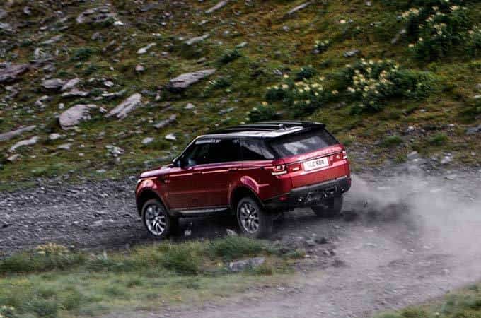Range Rover Sport on rugged terrain racing around the bend rear side view.