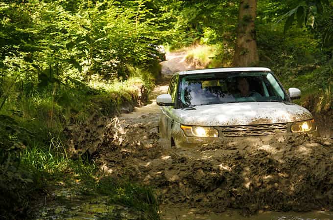 Land Rover wading through mud in the forest front view.