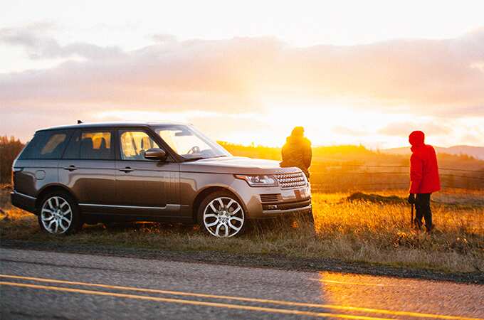Range Rover pulled over on the side of a country road at sunset. 