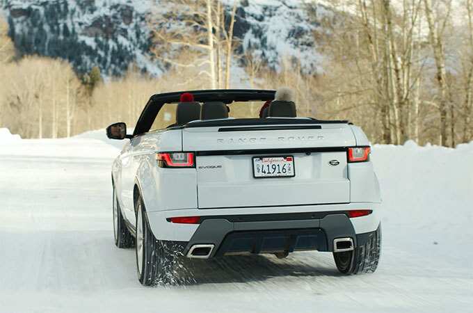 Range Rover Evoque Convertible top down driving on snow rear view.