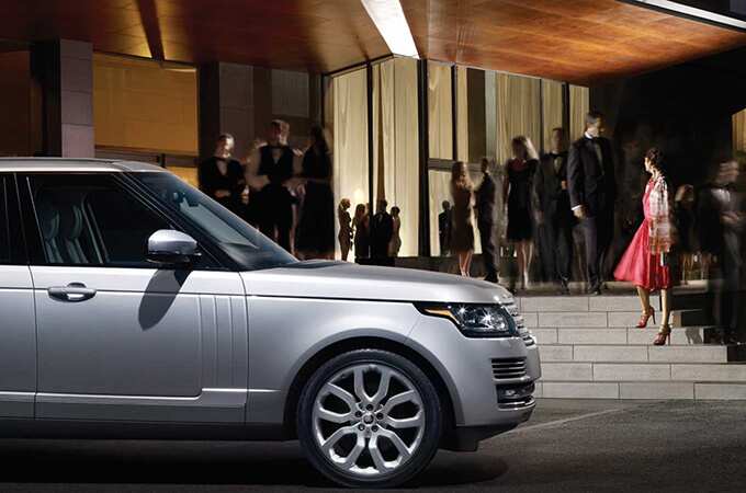 Range Rover in front of the entrance of a building hosting a formal event.
